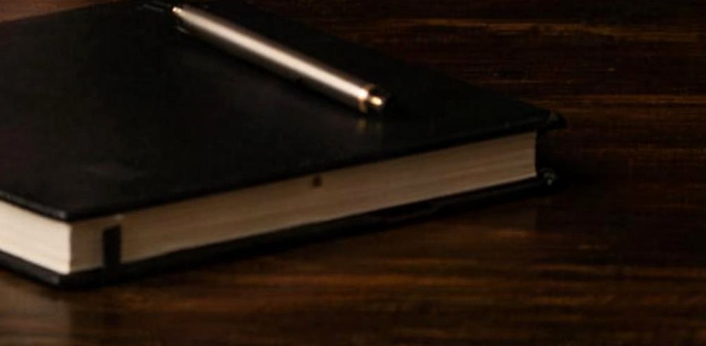 Notebook with a pen on dark wood
